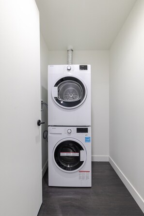 Eine kompakte, wendige Waschmaschine in einem schmalen Flur mit dunklem Boden.