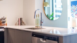 Una cucina moderna con lavello in acciaio inossidabile, uno specchio rotondo e una lavastoviglie.