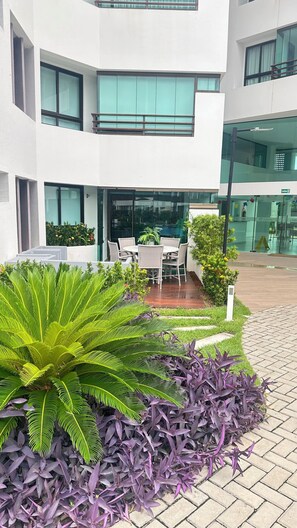 Ein modernes Gebäude mit einer Terrasse, die Gartenmöbel und üppiges Grün bietet.