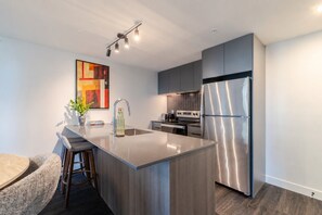 A modern kitchen with a central island, stainless steel appliances, and a contemporary design. - Montreal Skyline Escape | Free Parking & Pool (Montréal)