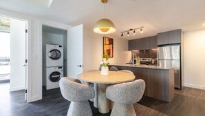 Een moderne keuken met een inbouwoven, een koelkast en een eethoek met een ronde tafel en twee stoelen.