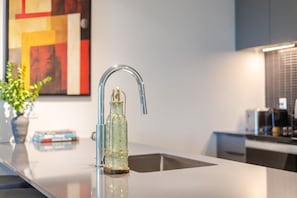 Eine moderne Küche mit einem Edelstahlarmaturen, einer Glasflasche und einer Vase mit Grünpflanzen.