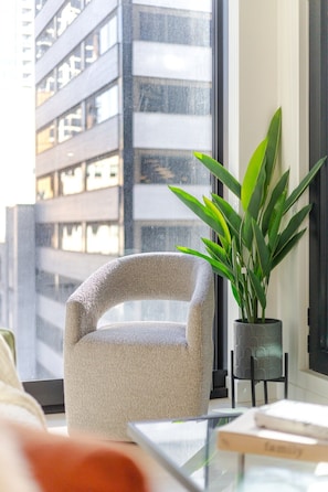 Uma sala de estar moderna com uma poltrona texturizada, uma planta em vaso e uma mesa de centro de vidro.