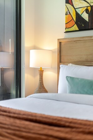 Ein Hotelzimmer mit Bett, Lampe und einem Gemälde an der Wand.