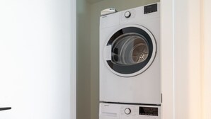 A laundry room with two stacked front-loading washing machines. - Executive Apartment | Free Parking & Pool (Montreal)
