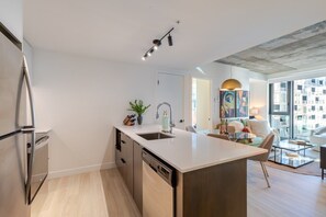 Een moderne keuken met een inbouwvaatwasser, een spoelbak en een eethoek met een glazen tafel en stoelen.