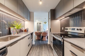 Eine moderne Küche mit Einbauofen, Spüle und Essbereich mit rundem Tisch und Stühlen.