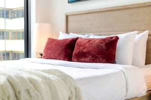 Ein Hotelzimmer mit Bett, Kopfteil und Fenster mit Blick auf Gebäude.
