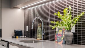 Une cuisine moderne avec un évier en acier inoxydable, une machine à café et une plante en pot.