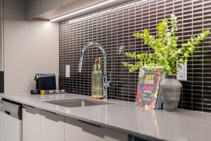 A modern kitchen with a stainless steel sink, a coffee machine, and a potted plant. - City View Oasis | Free Parking & Pool (Montreal)