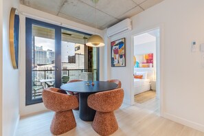 A modern dining area with a round table, two chairs, a pendant light, and a view of the city through large windows. - Downtown Comfort Apartment | Free Parking & Pool (Montréal)