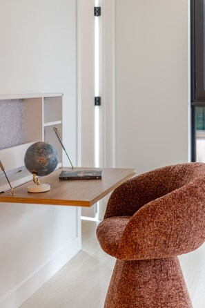 Une pièce moderne avec un bureau en bois, un globe terrestre et un fauteuil marron.