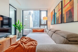 Habitació d'hotel moderna amb un llit gran, televisió, una planta i vista a la ciutat.