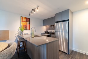 Une cuisine moderne dotée d’un îlot central, d’appareils électroménagers en acier inoxydable et d’un design contemporain.