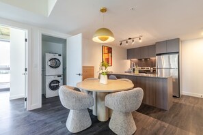 A modern kitchen with a central island, built-in appliances, and a dining area with a round table and two chairs. - Downtown Serenity Stay | Free Parking & Pool (Montréal)