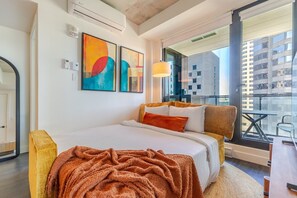 A modern hotel room with a large bed, a balcony with a view of the city, and abstract art on the wall. - Downtown Serenity Stay | Free Parking & Pool (Montréal)