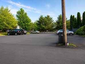Ein Parkplatz mit Fahrzeugen, einem hölzernen Strommast und einer Steinmauer im Hintergrund.