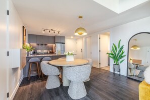 Una cuina moderna amb armaris grisos, una illa central i una zona de dinar amb taula rodona i cadires.