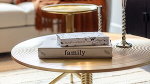 A cozy living room with a sofa, a coffee table with books, and a television. - Golden Stay | Free Parking & Pool (Montreal)
