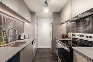 Una cucina moderna con piano cottura in acciaio inossidabile, forno integrato, frigorifero e lavello con rubinetto.