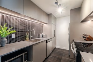 A modern kitchen with a built-in oven, a sink, and a stove. - Montreal Skyline Escape | Free Parking & Pool (Montreal)