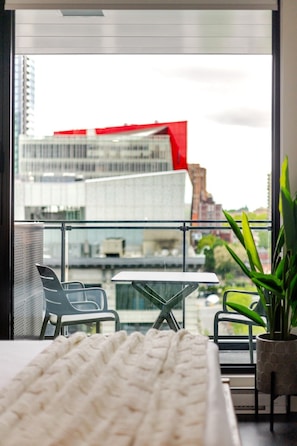A modern balcony with a view of a cityscape, including a red building. - Downtown Poolside Haven | Free Parking & Pool (Montreal)