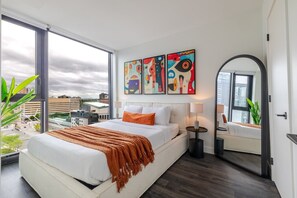 A modern hotel room with a large bed, a city view, and abstract art on the wall. - Downtown Poolside Haven | Free Parking & Pool (Montreal)