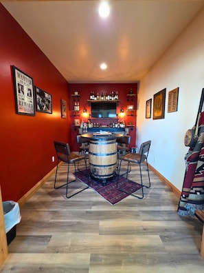 A bar area with a wooden barrel table, chairs, and a TV mounted on the wall. - Bear Claw Mountain House (Livingston)