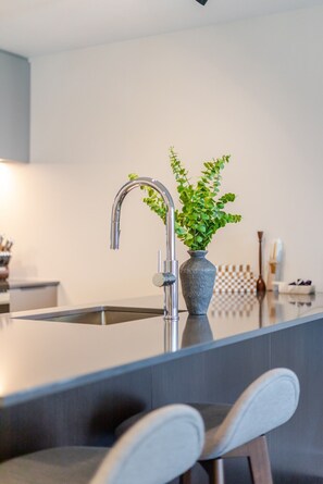 Eine moderne Küche mit Armatur aus Edelstahl, einem Blumentopf und einer karierten Tischdecke.