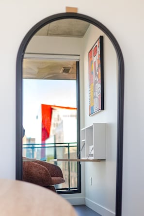 A room with a large window, a view of the city, a red flag outside, and a white shelf unit. - Luxury Urban Retreat | Pools Gym Sauna & Balcony (Montreal)