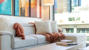Un salon moderne avec un canapé, des coussins, un plaid et une table basse.