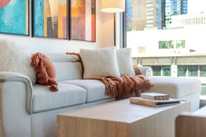 A modern living room with a sofa, pillows, a throw blanket, and a coffee table. - Luxury Urban Retreat | Pools Gym Sauna & Balcony (Montreal)