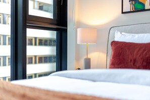 Una habitación de hotel con una cama, una ventana y una lámpara.