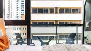 Et hotelværelse med balkon, seng, bord og stole.