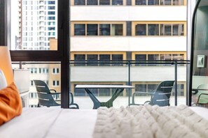A hotel room with a balcony, a bed, a table, and chairs. - Modern City Retreat | Balcony + Resort Amenities (Montreal)