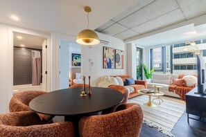 A modern living room with a round table, sofas, and a TV. - Modern City Retreat | Balcony + Resort Amenities (Montreal)