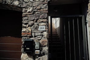 A stone wall with a 24/7 sign, a door with vertical bars, and a mailbox. - With a breathtaking lake view, brand new apartment for families and couples (Cavaion Veronese)