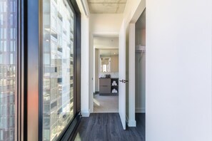 Ein modernes Interieur mit einem großen Fenster, einer Küchenzeile inklusive Arbeitsplatte und Schränken sowie einem Flur, der zu einer Tür führt.