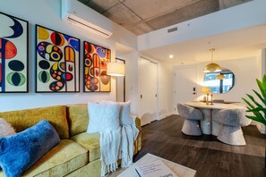 A modern living room with a sofa, a round table, and abstract art on the wall. - Elegant Downtown Stay | Pools Gym & Rooftop (Montreal)
