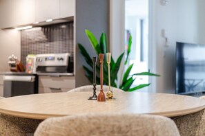 A modern kitchen with a dining table, chairs, and a plant. - Elegant Downtown Stay | Pools Gym & Rooftop (Montreal)