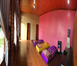 Una habitación con suelo de madera, pared rosa y cama con ropa de cama colorida.