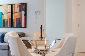 A modern dining area with a glass table, four chairs, and two candlesticks. - Luxury 2BR Condo w/ Pools, Gym, Cinema and Balcony (Montreal)