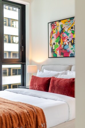 Ein Hotelzimmer mit einem Bett, einem Fenster, einem Gemälde und einer Lampe.