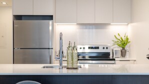 Eine moderne Küche mit einem Edelstahl-Kühlschrank, einem Backofen und einem Spülbecken mit Armatur.