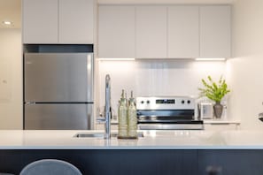 Eine moderne Küche mit einem Edelstahl-Kühlschrank, einem Backofen und einem Spülbecken mit Armatur.