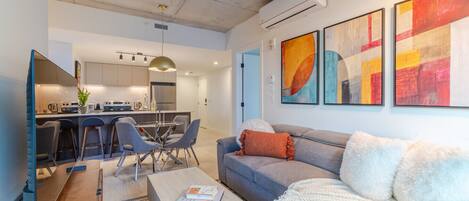 Uma sala de estar moderna com sofá, mesa de centro e uma área de jantar com cadeiras e mesa.