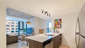 A modern kitchen with a central island, built-in dishwasher, and a refrigerator. - Urban Luxe Stay | Free Parking (Montréal)