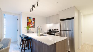 Una cocina moderna con una isla central, electrodomésticos de acero inoxidable y una obra de arte contemporánea en la pared.