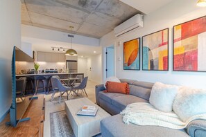 Ein modernes Wohnzimmer mit einer Couch, einem Couchtisch und einem Essbereich mit Stühlen und einem Tisch.