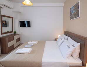 Habitación de hotel con una cama, un televisor, un espejo, un aparador y un cuadro en la pared.